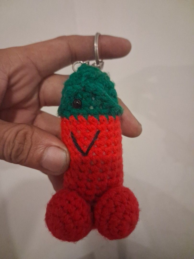 Crocheted Penis Keychain - Novelty Gag Gift (Category: Handmade Craft) located in Manila. Submitted by beardedbot (Listing ID 1447418264, Image 2). Description: - Handmade crocheted keychain - Red body with green head - Features a cute stitched face - Ideal as a funny gift or quirky accessory - Great for keys or bags - Unique and eye-catching design issue: missing one eye.