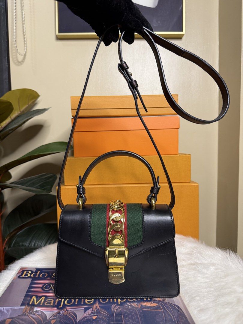 Gucci Black Sylvie Top Handle Bag (Category: Luxury Bags & Wallets) located in Caloocan City. Submitted by marj_bags (Listing ID 1447417232, Image 1). Description: - Authentic Black Gucci Sylvie Bag - Signature Green and Red Stripe - Elegant Gold Chain Detail - Versatile Top Handles and Detachable Shoulder Strap - Comes with Original Dust Bag - Ideal for Day-to-Night Wear.