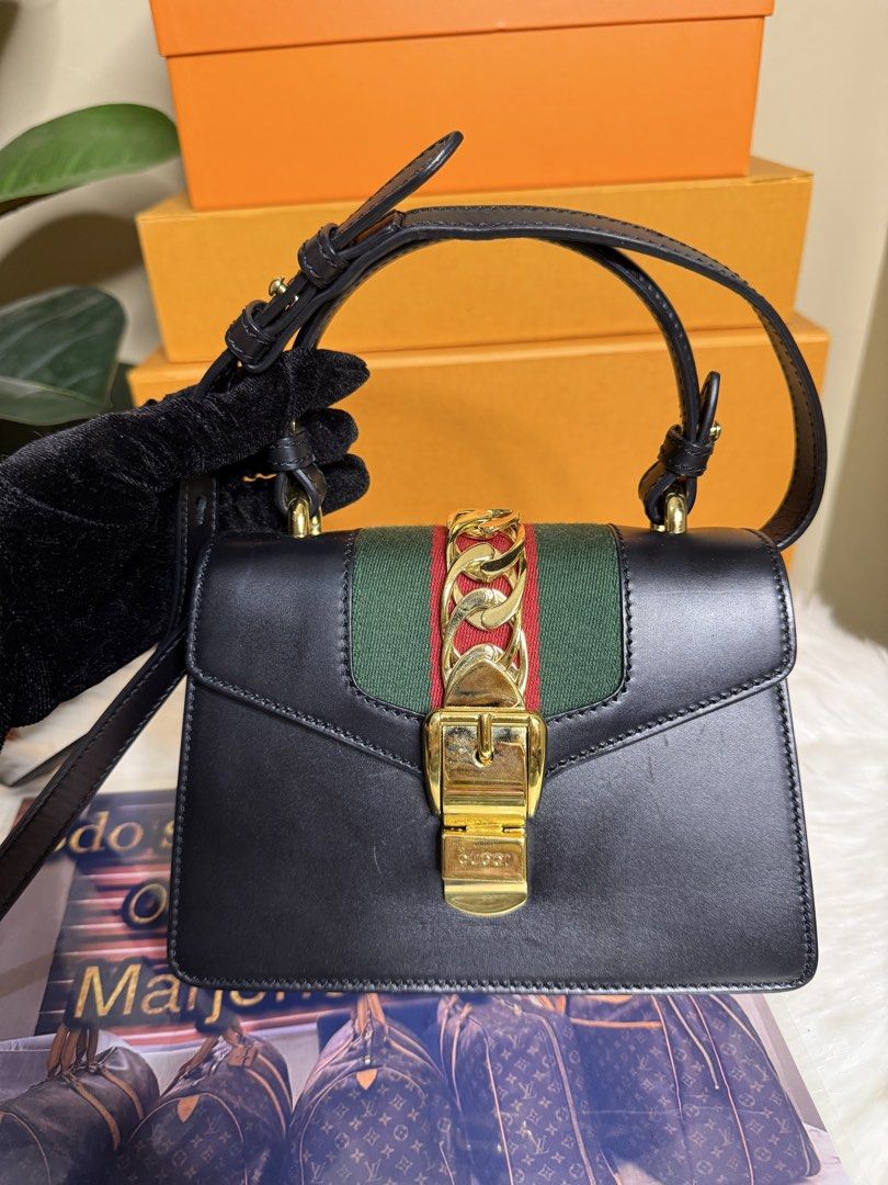 Gucci Black Sylvie Top Handle Bag (Category: Luxury Bags & Wallets) located in Caloocan City. Submitted by marj_bags (Listing ID 1447417232, Image 2). Description: - Authentic Black Gucci Sylvie Bag - Signature Green and Red Stripe - Elegant Gold Chain Detail - Versatile Top Handles and Detachable Shoulder Strap - Comes with Original Dust Bag - Ideal for Day-to-Night Wear.