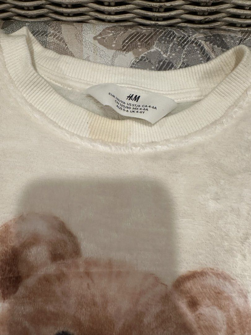 H&M Teddy Bear Fleece Sweatshirt (Category: Babies & Kids Fashion) located in Manila. Submitted by bubuamponin (Listing ID 1447299195, Image 2). Description: - Cream colored fleece sweatshirt from H&M - Features a cute teddy bear graphic with a black bow - Long sleeves and crew neck - Soft and cozy material, great for casual wear - Measurements: Length 18", Chest 14", Sleeve 15" - Note: Slight yellow stain near the collar.