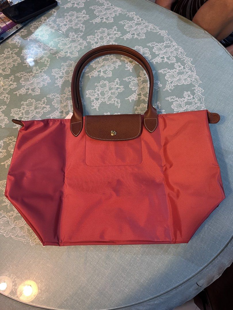 Longchamp Le Pliage Shoulder Bag (Category: Luxury Bags & Wallets) located in Bulacan. Submitted by memayeselfinday (Listing ID 1447468832, Image 3). Description: - Classic Longchamp Le Pliage shoulder bag - Small size - Lovely pinkish-red color - Brown leather handles and trim - Folds flat for easy storage - Great everyday bag.