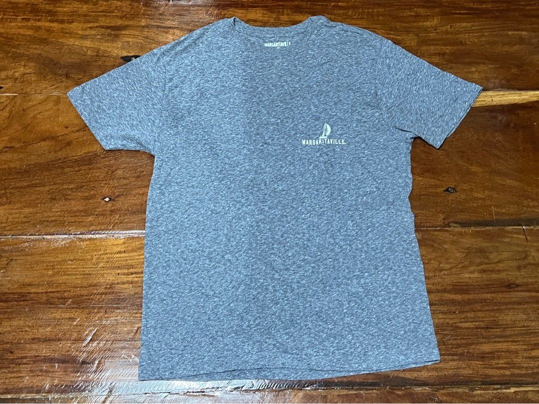 Margaritaville Graphic T-Shirt (Category: Tshirts & Polo Shirts ) located in Leyte. Submitted by jcatle (Listing ID 1447453984, Image 1). Description: - Grey heather t-shirt - Fits M-L - Fun 'It's 5 O'Clock Somewhere' graphic on the back - Graphic includes sailboat and palm trees - Small Margaritaville logo on the front chest - Ideal for casual wear or a beach vibe.