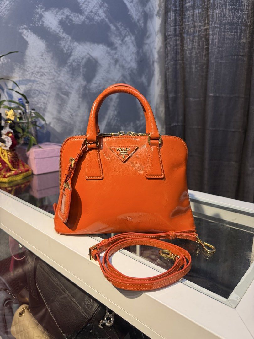 Prada Orange Patent Leather Top Handle Bag with Strap (Category: Luxury Bags & Wallets) located in Santiago. Submitted by twicebutnice03 (Listing ID 1447397683, Image 1). Description: - Authentic Orange Prada Bag - Glossy Patent Leather Finish - Includes Detachable Shoulder Strap - Elegant Gold Hardware Details - Versatile: Ideal for everyday or evening wear - Spacious Interior for Essentials - A Timeless Addition to Your Collection.