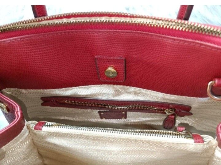 Prada Saffiano Leather Galleria Bag (red) (Category: Luxury Bags & Wallets) located in Baliuag. Submitted by mnldecluttter (Listing ID 1447466483, Image 3). Description: - Prada bag in vibrant red - Made from textured leather - Zip-top closure - Two top handles - Interior zip pocket - Central compartment - Gold-tone hardware- some fader - Versatile vintage for everyday or special occasions, genuine leather. - 4 hardware at the bottom with Prada c