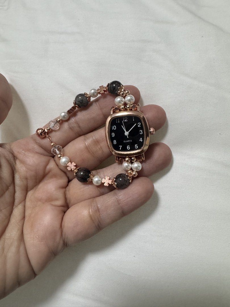 Rose Gold Quartz Watch with Beaded Bracelet (Category: Women's Watches) located in Guagua. Submitted by dixie_1028 (Listing ID 1447310384, Image 2). Description: - Unique square face watch - Black dial with rose gold casing - Bracelet with beads, pearls, and flower charms - Quartz movement - Perfect accessory for a distinctive look.