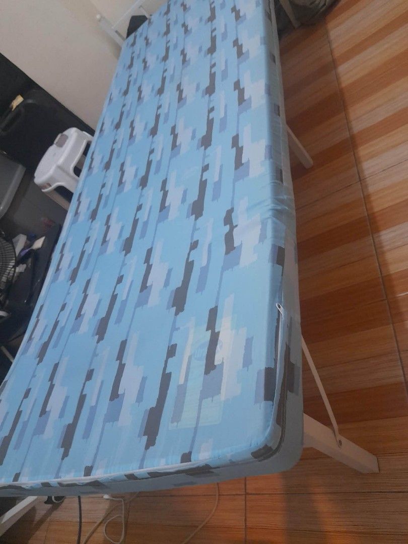 Single Bed Frame with Blue Camo Mattress (Category: Bed Frames & Mattresses) located in Manila. Submitted by dayanghira00486 (Listing ID 1447424813, Image 2). Description: - Single bed frame - White metal construction - Includes comfortable mattress with blue camouflage pattern -Size 30cm wide x 74cm length -Mattress covered with a fitted sheet - Ideal for small rooms or guest bedrooms - Easy to assemble, foldable in half.