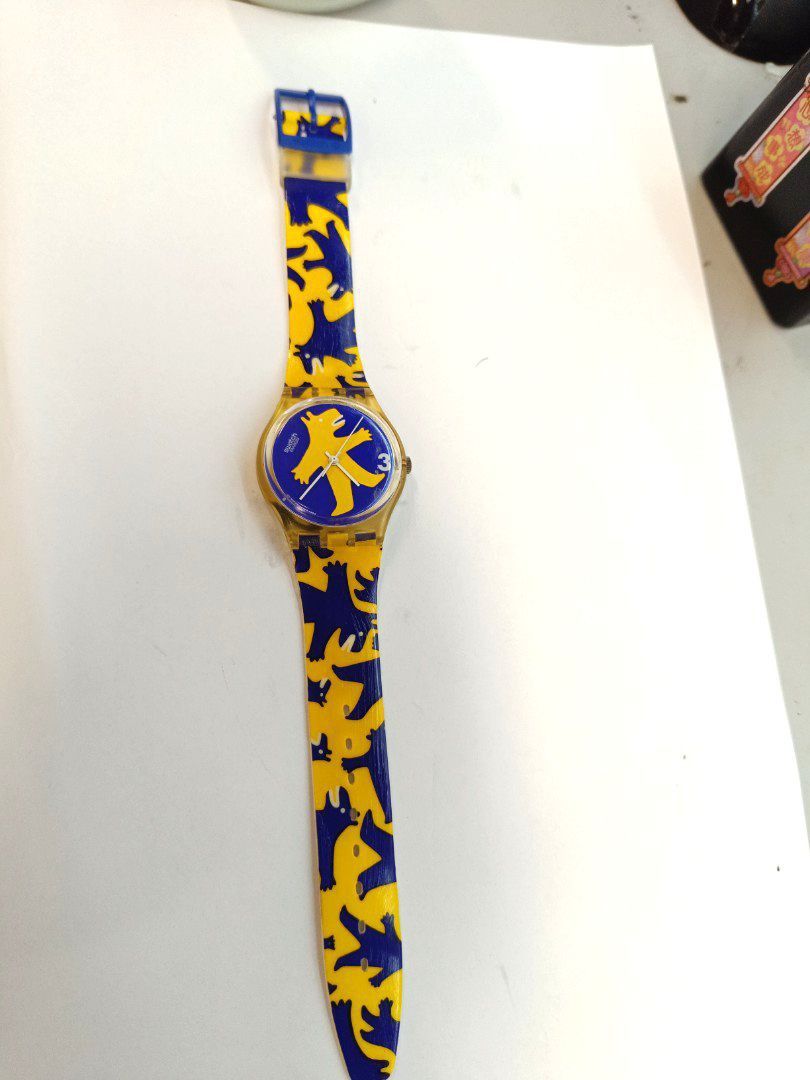 Swatch Gent BESTIONE （分類：手錶）位於 Hong Kong。 由 tomboyos10 提交（商品編號 1447372398，圖片 2）。簡介： 這是一款 Swatch Gent BESTIONE (型號 GJ112) 手錶，其特色是錶盤上鮮豔的黃藍色熊造型設計。 推出年份：此款式於 1994 年推出。 設計師：該設計由藝術家 Gabriella Giandelli 創作。 技術規格：錶殼直徑為 34 公釐，厚度為 8.75 公釐，具備 3 巴的防水性能。。