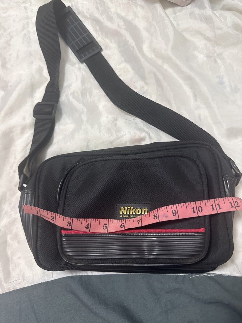 2027 Nikon Camera Bag (Category: Camera Bags & Carriers) located in Silang. Submitted by sari2bilina (Listing ID 1452707191, Image 1). Description: - Black Nikon camera bag - Front pocket with ribbed detail - Adjustable strap - Spacious main compartment for camera and accessories - Dimensions: Approx. 10" (L) x 6" (H) x 4" (D).