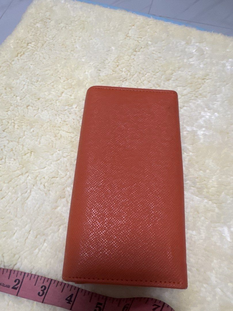 2027 Prada Orange Wallet (Category: Luxury Bags & Wallets) located in Silang. Submitted by sari2bilina (Listing ID 1433940897, Image 3). Description: - not sure if Authentic Prada orange wallet - Multiple card slots and cash compartments - Includes a zippered pocket - Crafted from textured leather - Interior lining with Prada logo - Secure snap closure - Clear ID window with flaws last 2 pics .