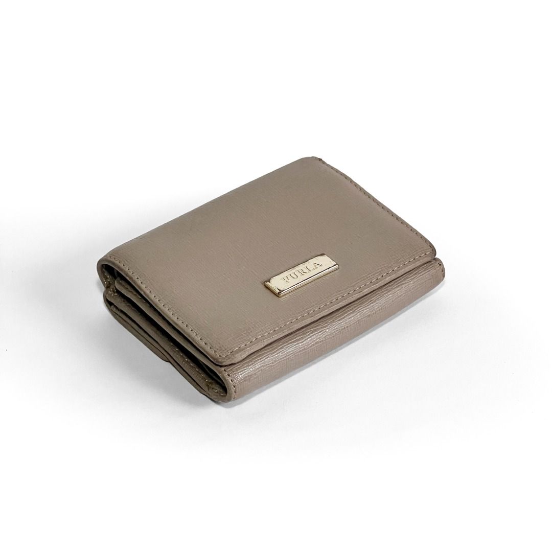 🔴 Sold | Authentic Furla Gray Saffiano Leather Compact Trifold Wallet (Category: Luxury Bags & Wallets) located in Malabon City. Submitted by k.1006 (Listing ID 1440863667, Image 1). Description: • Authentic Furla compact wallet • Gray / taupe-gray leather • Genuine leather construction • Saffiano-textured finish • Compact trifold wallet style • Branded Furla front metal logo plate • Branded Furla hardware details • Black and white tag inside • 