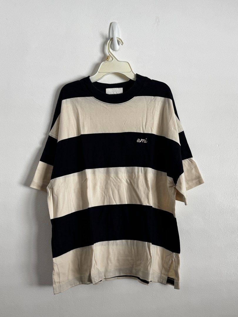 AMI Paris Striped T-shirt (Category: Tshirts & Polo Shirts ) located in Pasig City. Submitted by archive.project (Listing ID 1452772337, Image 1). Description: - Brand: AMI Paris - Color: Black and Cream Stripes - Design: Signature AMI logo embroidered on chest - Fit: Relaxed, comfortable for everyday wear - Material: 100% Cotton - Styling: Versatile, pairs well with jeans or shorts - Size XS fits Relaxed Boxy Small - I purchased this from Hoodwi