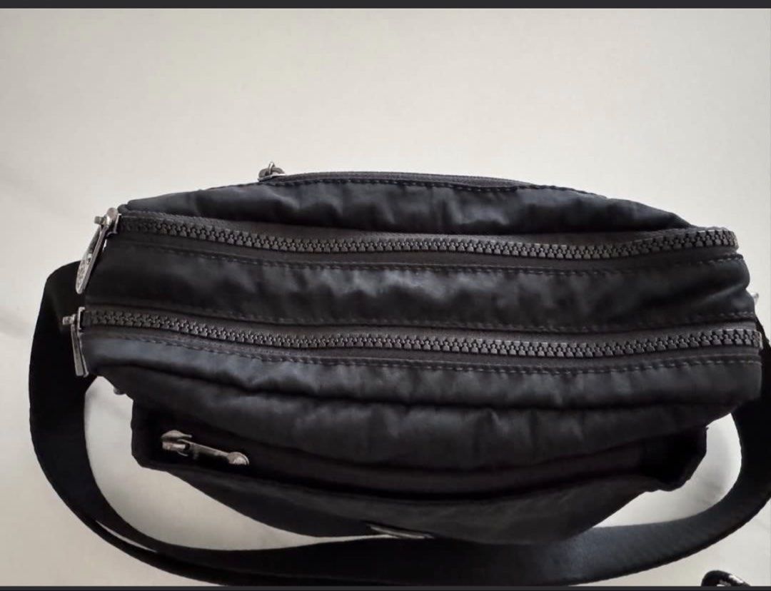 Authentic Kipling (Category: Cross-body Bags) located in Singapore. Submitted by blessingbabe (Listing ID 1452709672, Image 3). Description: - Authentic Kipling ABANU M Endless Black Crossbody Bag - Durable and lightweight nylon material - Classic and versatile black color - Adjustable crossbody strap for comfortable wear - Features the iconic Kipling monkey charm - Multiple zippered compartments for organization - Ideal for everyday use, travel,