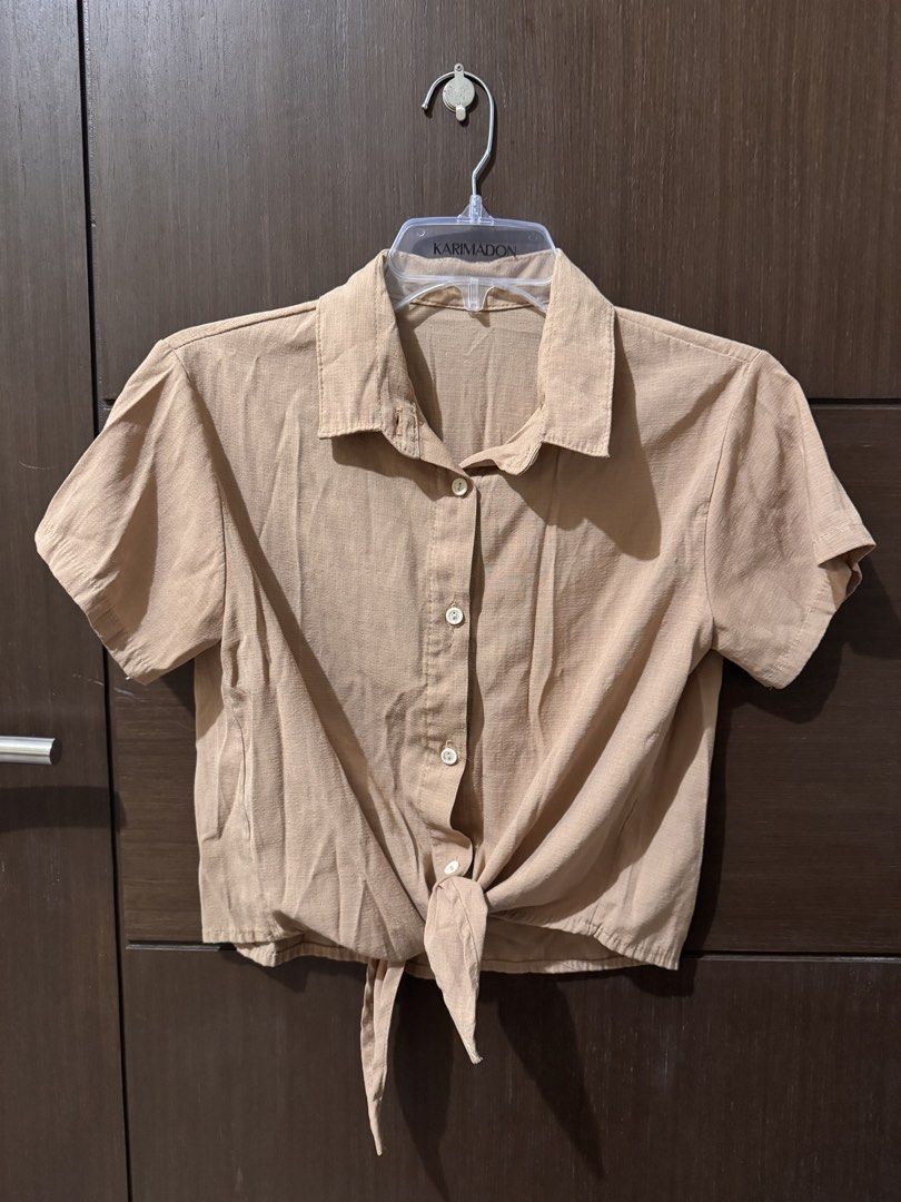 Beige Button Up Tie Front Polo Shirt Linen Blend (Category: Shirts) located in Quezon City. Submitted by ianne.declutter (Listing ID 1452832372, Image 3). Description: - Light brown short-sleeve button-up shirt - Collared neckline - Tie-front detail at the hem - Ideal for casual outfits.