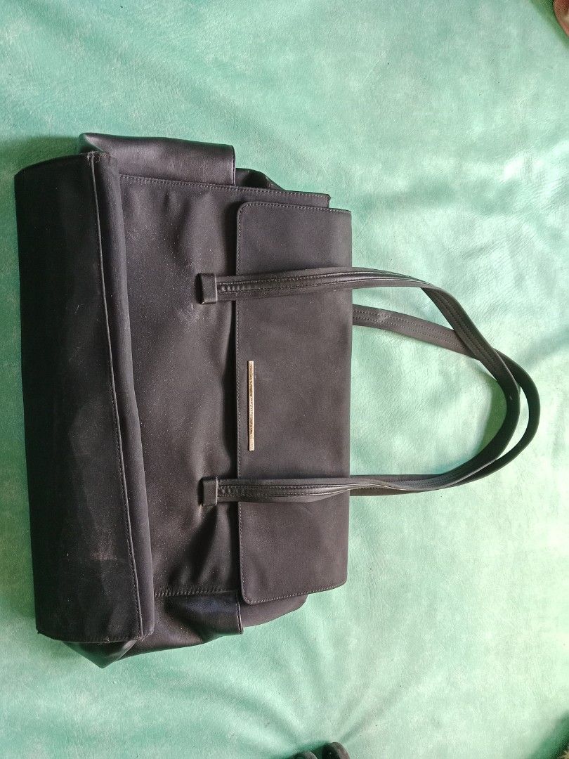 Black Tote Bag with Gold Accent (Category: Tote Bags) located in Manila. Submitted by narsonlineexpression (Listing ID 1452713820, Image 1). Description: - Classic black tote bag - Simple design with two shoulder straps - Small gold bar detail on the front - Plenty of space inside for essentials - Great for work or everyday use - Clean and ready for a new owner.