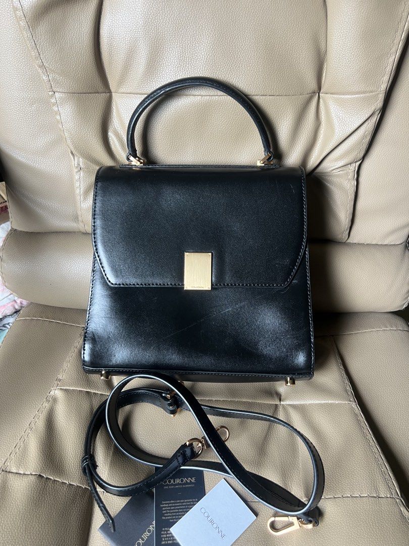 Couronne Black Leather Top Handle Bag with Shoulder Strap (Category: Shoulder Bags) located in Saravia. Submitted by clynlyn (Listing ID 1452767318, Image 1). Description: - Genuine black leather Couronne handbag - Elegant gold clasp closure - Comfortable top handle - Includes a detachable shoulder strap for versatility - Interior zippered pocket for secure storage - Stylish gold hardware details - Timeless and clean design - Ideal for both every