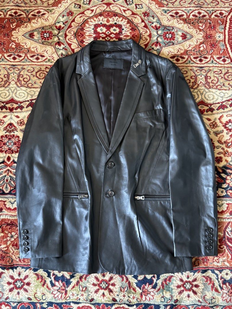 Prada - Tactical - Lambskin Leather Blazer (Category: Luxury Apparel) located in San Fernando. Submitted by larchivefeminine (Listing ID 1452716814, Image 1). Description: Prada - Tactical - Lambskin Leather Blazer Collared Zipper / Pockets Fresh Leather Size on tag : 52 Dimensions Width : 21.5in Length : 27in Sleeve : 25in Shoulder : 18in Condition : 9/10 No major flaws Soft Leather Made in : China Material : Lambskin Zipper : Opti Color : Black