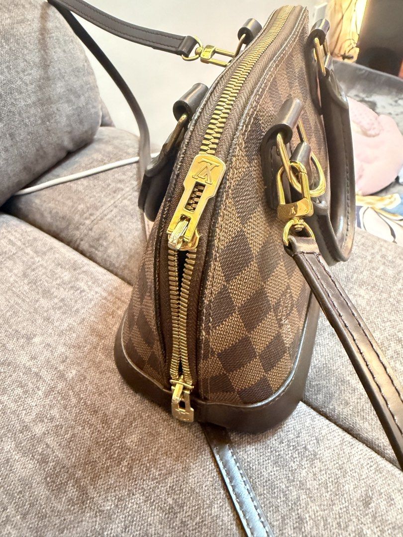Alma bb ebene (Category: Luxury Bags & Wallets) located in Manila. Submitted by miguelaine89171 (Listing ID 1453034829, Image 3). Description: Item: Alma Bb damier ebene Inclusion: box, paper bag, dust bag, lock and key, 1 extra strap sling from LV. Specific flaw: Interior shows moderate signs of use, including visible staining and dirt transfer on the red lining. Slip pocket is clean and intact. Zipper runs smoothly. Exterior canvas remains in v