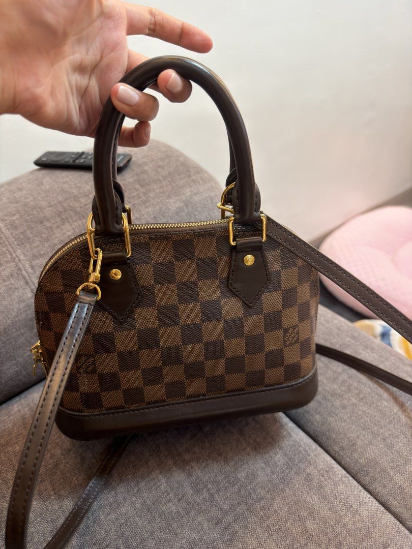 Alma bb ebene (Category: Luxury Bags & Wallets) located in Manila. Submitted by miguelaine89171 (Listing ID 1453034829, Image 1). Description: Item: Alma Bb damier ebene Inclusion: box, paper bag, dust bag, lock and key, 1 extra strap sling from LV. Specific flaw: Interior shows moderate signs of use, including visible staining and dirt transfer on the red lining. Slip pocket is clean and intact. Zipper runs smoothly. Exterior canvas remains in v