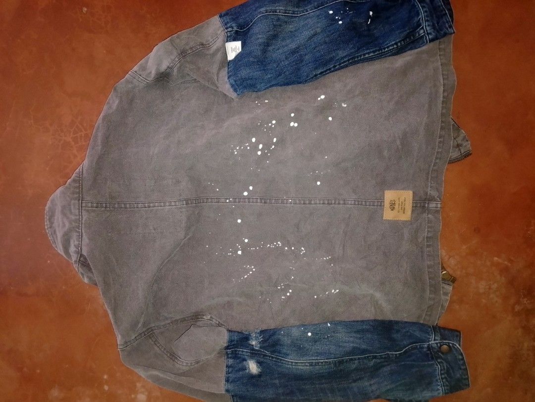 MADNESS Standard Daily Apparel Jacket (Category: Coats, Jackets and Outerwear) located in Caloocan City. Submitted by ndkph (Listing ID 1452951177, Image 2). Description: - Grey and blue denim jacket from MADNESS - Features unique paint splatters all over - Inner label has a wilderness survival guide print - Distinctive patchwork design - Ideal for casual wear.
