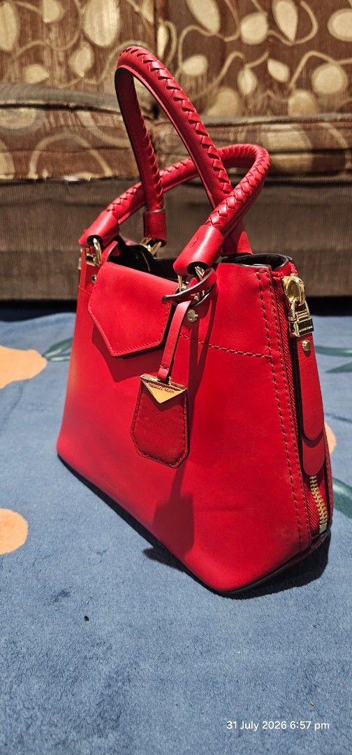 Michael Kors Red Leather Satchel Handbag (Category: Luxury Bags & Wallets) located in Baguio. Submitted by msgold2601 (Listing ID 1453048886, Image 2). Description: - Authentic Michael Kors red leather satchel - Elegant gold hardware details - Includes a detachable shoulder strap for versatile carrying - Secure top zip closure - Stylish braided top handles - Ample interior space for your essentials - Ideal for both everyday use and evening outing