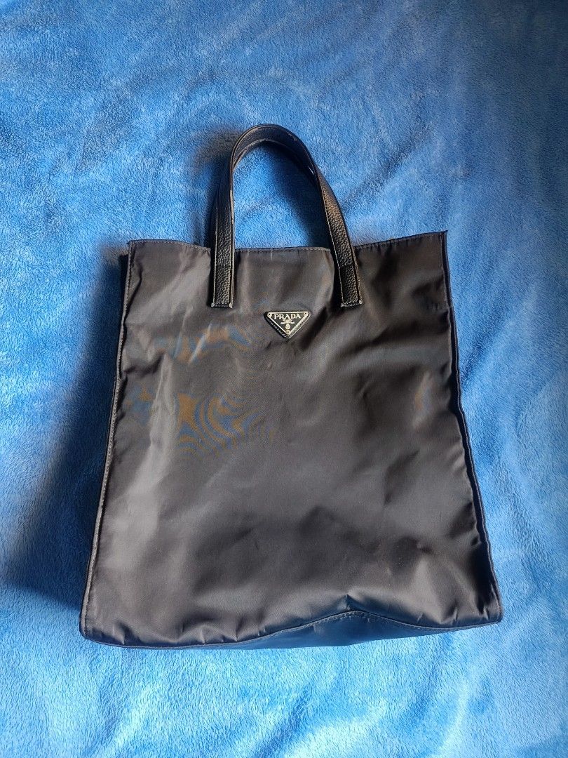 Prada Nylon Tote Bag (Category: Luxury Bags & Wallets) located in Cagayan de Oro. Submitted by wilddragon.1ae9b9 (Listing ID 1452933013, Image 1). Description: - Classic black Prada tote bag - Durable nylon material with leather handles - Iconic Prada triangle logo on the front - Spacious interior for everyday essentials - Versatile for work or casual outings.