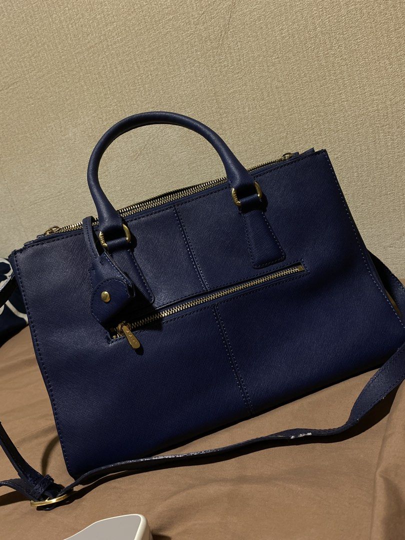 Sisley Navy Blue Leather Tote Bag (Category: Tote Bags) located in Manila. Submitted by cdb_22 (Listing ID 1453008808, Image 3). Description: Chic navy blue Sisley tote bag with saffiano leather texture and gold hardware. Features top handles, a detachable strap, multiple zippered pockets, and protective base studs. Spacious interior..