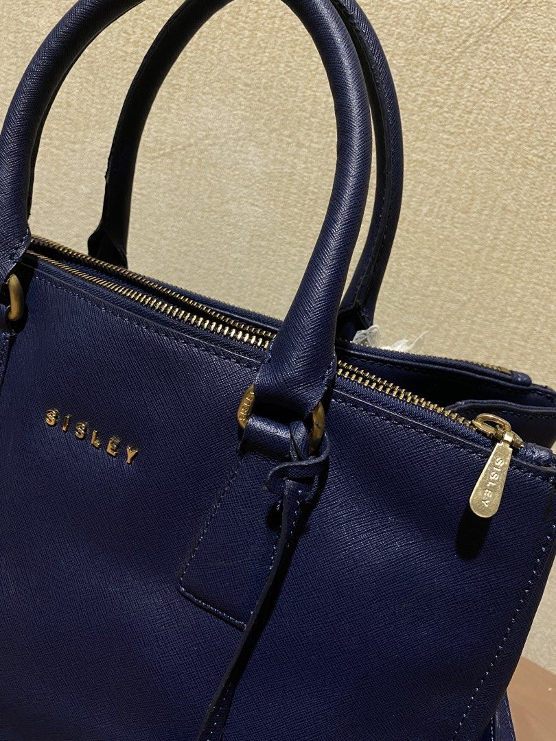 Sisley Navy Blue Leather Tote Bag (Category: Tote Bags) located in Manila. Submitted by cdb_22 (Listing ID 1453008808, Image 2). Description: Chic navy blue Sisley tote bag with saffiano leather texture and gold hardware. Features top handles, a detachable strap, multiple zippered pockets, and protective base studs. Spacious interior..