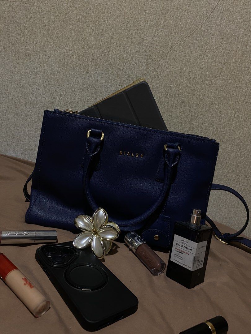 Sisley Navy Blue Leather Tote Bag (Category: Tote Bags) located in Manila. Submitted by cdb_22 (Listing ID 1453008808, Image 1). Description: Chic navy blue Sisley tote bag with saffiano leather texture and gold hardware. Features top handles, a detachable strap, multiple zippered pockets, and protective base studs. Spacious interior..