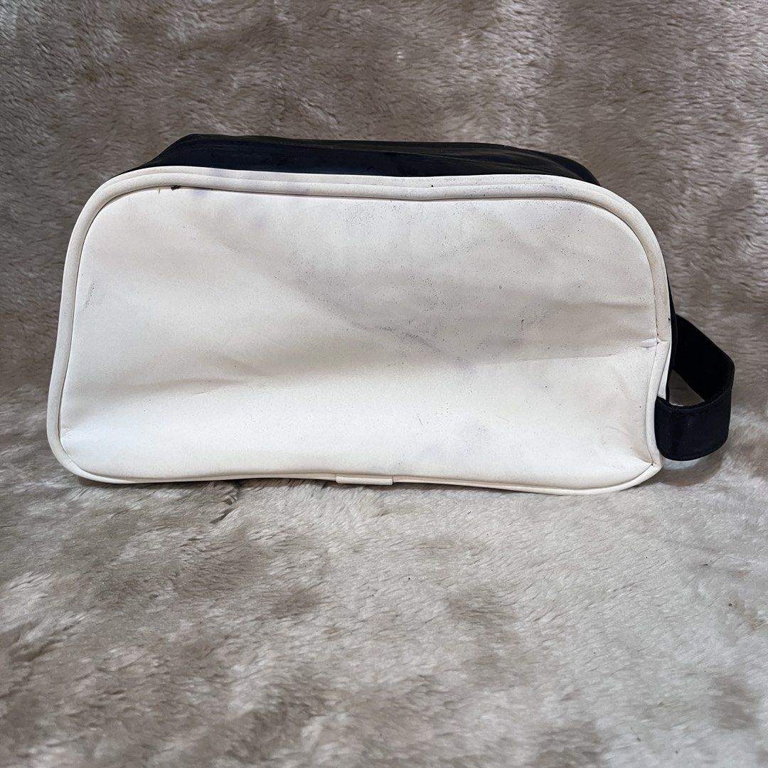 Titleist Golf Pouch Bag Black White (Category: Golf) located in Butuan. Submitted by dfgthriftology2.0 (Listing ID 1452985383, Image 3). Description: - Titleist pouch bag in black and white. - Main compartment with an internal zip pocket. - Zippers are in smooth working condition. - Exterior shows minor marks and scuffs from normal use. - Side handle is intact and functional. - Ideal for storing golf accessories or toiletries..