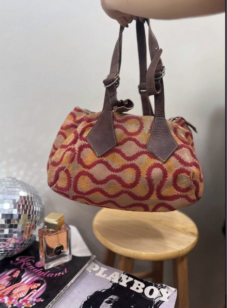 Vivienne Westwood Orb Pattern Handbag (Category: Luxury Bags & Wallets) located in Dagupan City. Submitted by shlyukha (Listing ID 1452986517, Image 2). Description: - Authentic Vivienne Westwood handbag - Features iconic orb pattern in red and orange - Genuine leather trim and handles - Secure zipper closure - Interior zip pocket for essentials - Perfect for everyday use - Shows some signs of wear on the leather, adding character.
