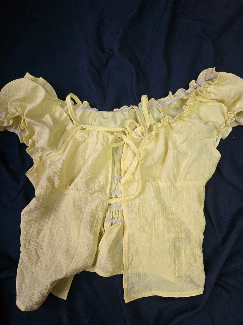 Yellow Off-Shoulder Puff Sleeve Tie Front Crop Top (Category: Blouses) located in Taguig. Submitted by prelovedchattelz (Listing ID 1452944731, Image 2). Description: - Cute yellow puff sleeve top - Off-shoulder design - Tie front with button details - Ruffled neckline and sleeves - Lightweight fabric, ideal for summer - Versatile styling with shorts or jeans.