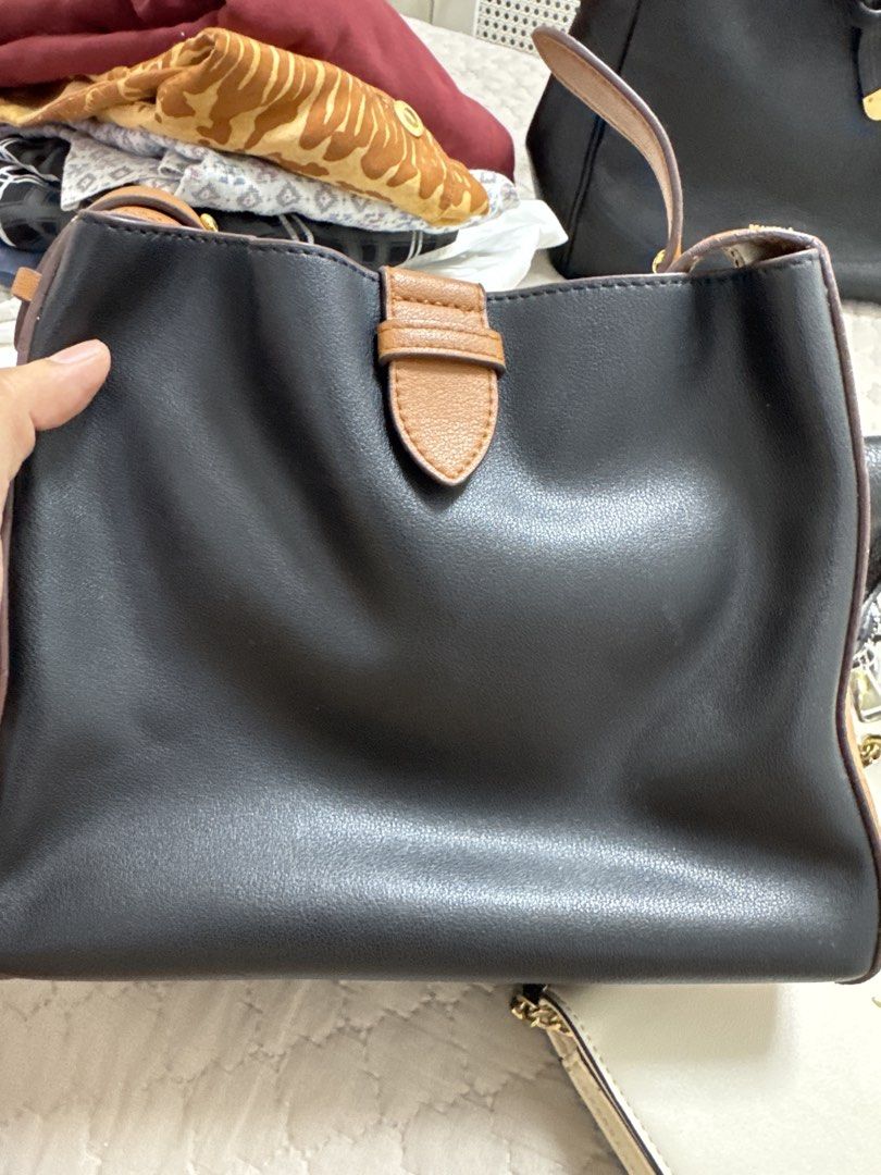 Black and Tan Leather Handbag (Category: Tote Bags) located in Santiago. Submitted by sissy.declutter (Listing ID 1447514343, Image 1). Description: - Stylish black leather handbag with elegant tan accents. - Features a secure and attractive buckle closure on the front. - Comes with an adjustable shoulder strap for comfortable carrying. - Offers a spacious interior, ideal for all your essentials. - Perfect for everyday use, blending style and pra