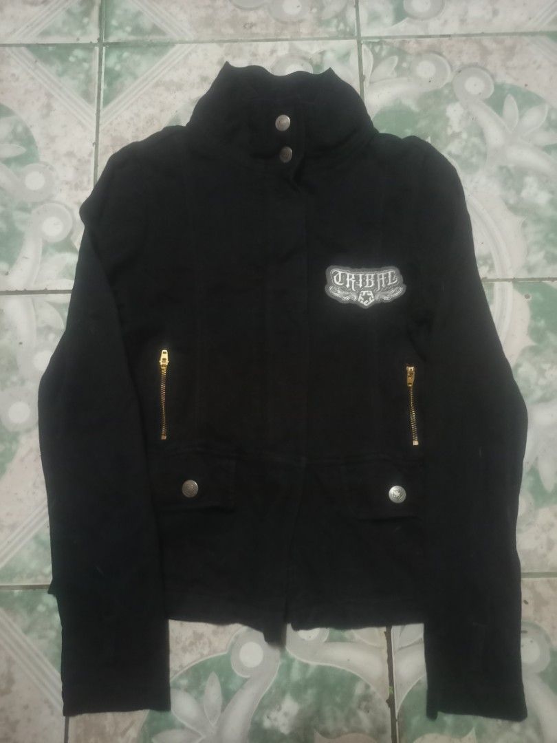 Black Tribal Jacket with Zipper Details (Category: Coats, Jackets and Outerwear) located in Cavite. Submitted by ronniel0943882 (Listing ID 1447637286, Image 1). Description: - Black jacket with a stylish stand-up collar. - Eye-catching gold zipper details on pockets and front. - Authentic 'Tribal' logo patch on the chest. - Secure button closure at the neck. - Estimated size: Medium. - Versatile for casual or edgy outfits..