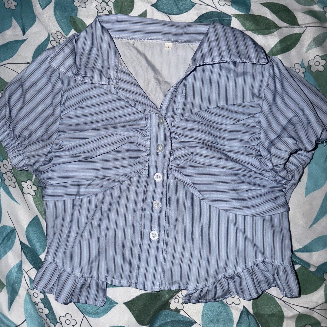 Blue Striped Ruched Button-Up Shirt with Ruffle Hem (Category: Shirts) located in Quezon City. Submitted by izanari (Listing ID 1447589672, Image 1). Description: - Adorable blue and white striped shirt - Features a flattering ruched front with button closure - Stylish short puff sleeves - Charming ruffle detail along the hem - Versatile: pairs perfectly with jeans or skirts - Adds a touch of flair and is easy to style.