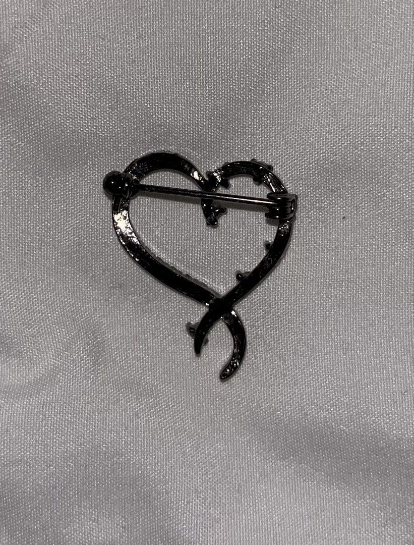 Heart Shaped Brooch with Rhinestones (Category: Brooches) located in Tabuk. Submitted by zenwolf-1867 (Listing ID 1447664257, Image 2). Description: - Cute heart-shaped brooch - Dark metal finish - Adorned with small clear rhinestones - Ribbon-like element wraps around the heart - Secure pin closure on the back - Adds a lovely sparkle to any outfit.