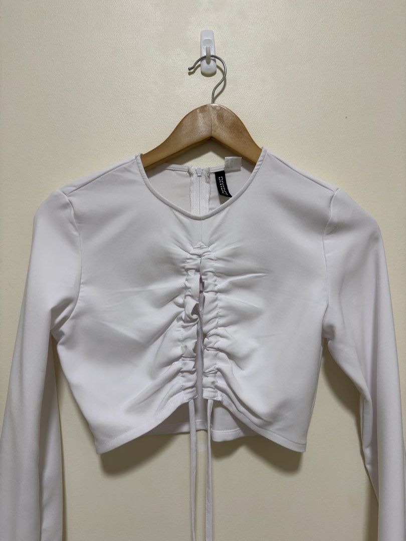 H&M White Ruched Long Sleeve Crop Top (Category: Longsleeves) located in Manila. Submitted by seayouncey (Listing ID 1447656767, Image 3). Description: - Brand: H&M - Style: Long sleeve crop top - Color: White - Features: Ruched front with drawstring, bell sleeves - Closure: Zipper at the back - Versatile: Perfect for dressing up or down.