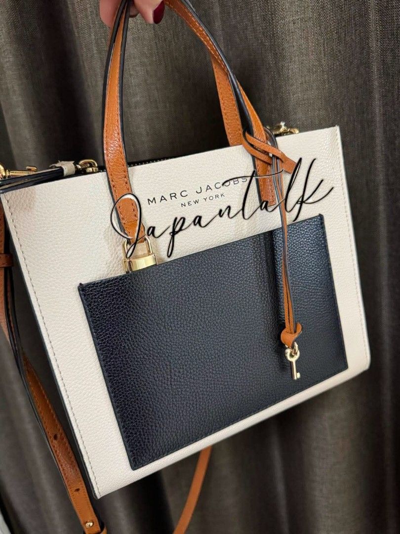 Marc Jacobs New York Tote Bag (Category: Luxury Bags & Wallets) located in Bulacan. Submitted by vintage_purge (Listing ID 1447523563, Image 2). Description: - Stylish Marc Jacobs tote bag - Elegant beige and black colorblock design - Comfortable tan leather handles and strap - Convenient front pocket with a cute key charm - Chic gold hardware details - Ideal for everyday wear and errands.