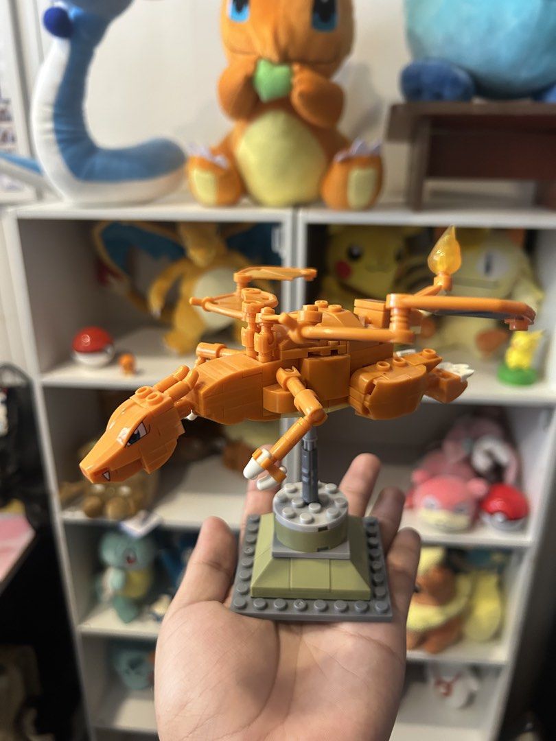 MEGA construx pokemon Charizard lego (Category: Lego & Building Sets) located in Lucena. Submitted by chobaps_ (Listing ID 1447488654, Image 2). Description: - Orange Charizard building block toy - Features blue and orange wings - Comes with a display stand - Ideal for any Pokemon fan - Previously displayed on a shelf - No original box included.