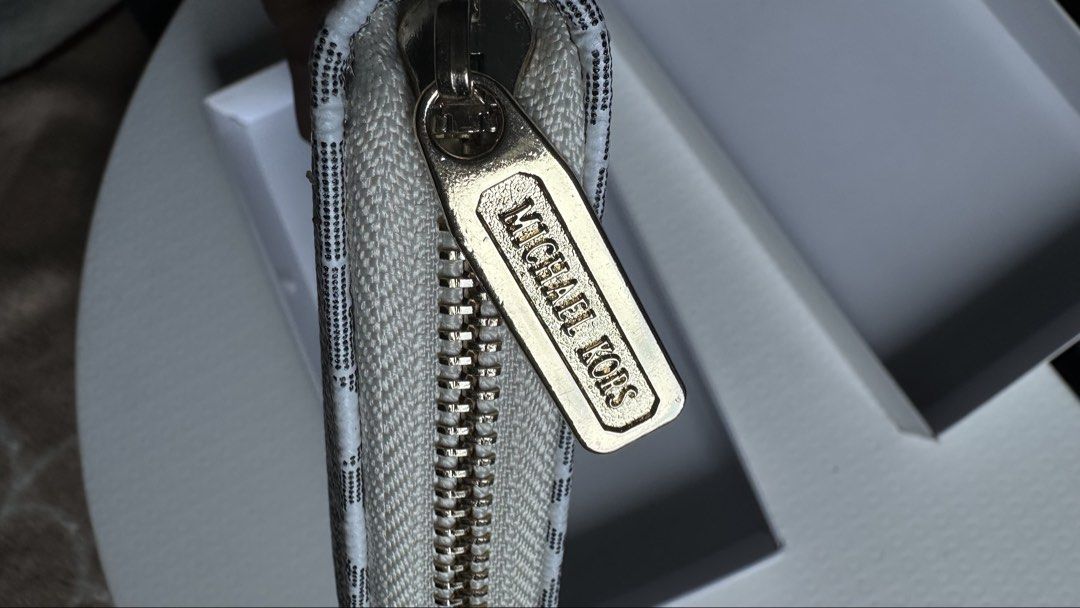 Michael Kors Monogram Zip Around Wallet (Category: Wallets & Card holders) located in Mandaluyong City. Submitted by TheWeekendProject (Listing ID 1447507678, Image 3). Description: - Michael Kors wallet - Classic MK monogram print (white & grey) - Gold hardware - Zip-around closure - Multiple interior card slots - Zippered coin pocket - Comes with original box - Ideal for organizing essentials - Great for gifting - Note: No tags inside and it is
