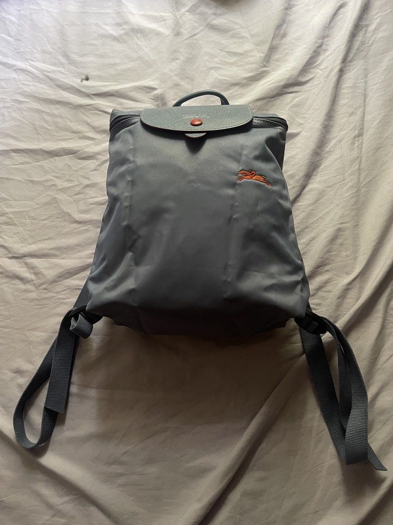 PRELOVED Longchamp Le Pliage Backpack BLUE GREY (Category: Backpacks) located in Pasay City. Submitted by epictiger.84b83d (Listing ID 1447489366, Image 1). Description: - Authentic Grey Longchamp Le Pliage Backpack - Durable Nylon Material with Leather Trim - Iconic Horse Logo Detail - Secure Zipper Closure with Snap Button Flap - Adjustable Shoulder Straps - Ideal for Everyday Use or Travel.