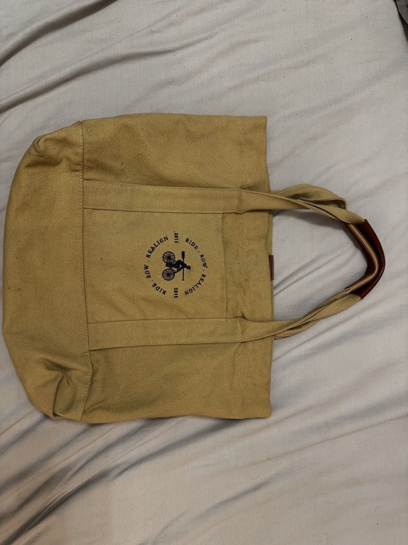 SADDLE ROW Canvas Tote Bag with Bicycle & Oars Graphic (Category: Tote Bags) located in Mandaluyong City. Submitted by ljcasinnn (Listing ID 1447642911, Image 1). Description: - Saddle Row Tan canvas tote bag - Features 'SEALIGN RIDE. ROW. REALIGN 2015' graphic with bicycle and oars - measurement in inches - Leather accents on handles - Interior pocket - Ideal for everyday use or as a beach bag.
