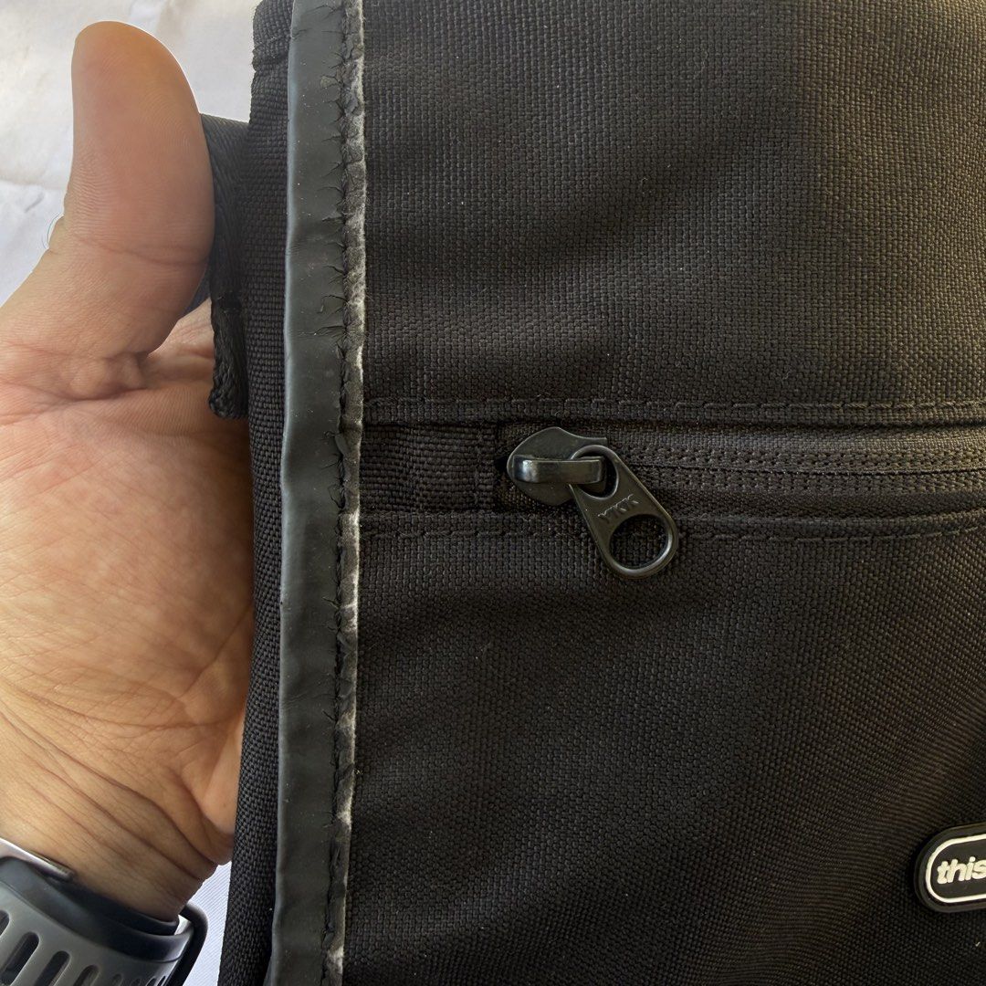 thisisneverthat Messenger Bag (Category: Sling Bags) located in Passi. Submitted by Trifft21 (Listing ID 1447553298, Image 3). Description: thisisneverthat Messenger Bag - Color: Black - Material: Durable Cordura fabric - Features: Main zippered compartment, front zippered pocket - Strap: Adjustable for comfortable wear - Condition: Great for daily use, shows some signs of wear on the trim Issue: Small leather cracks on sides as seen on picture P