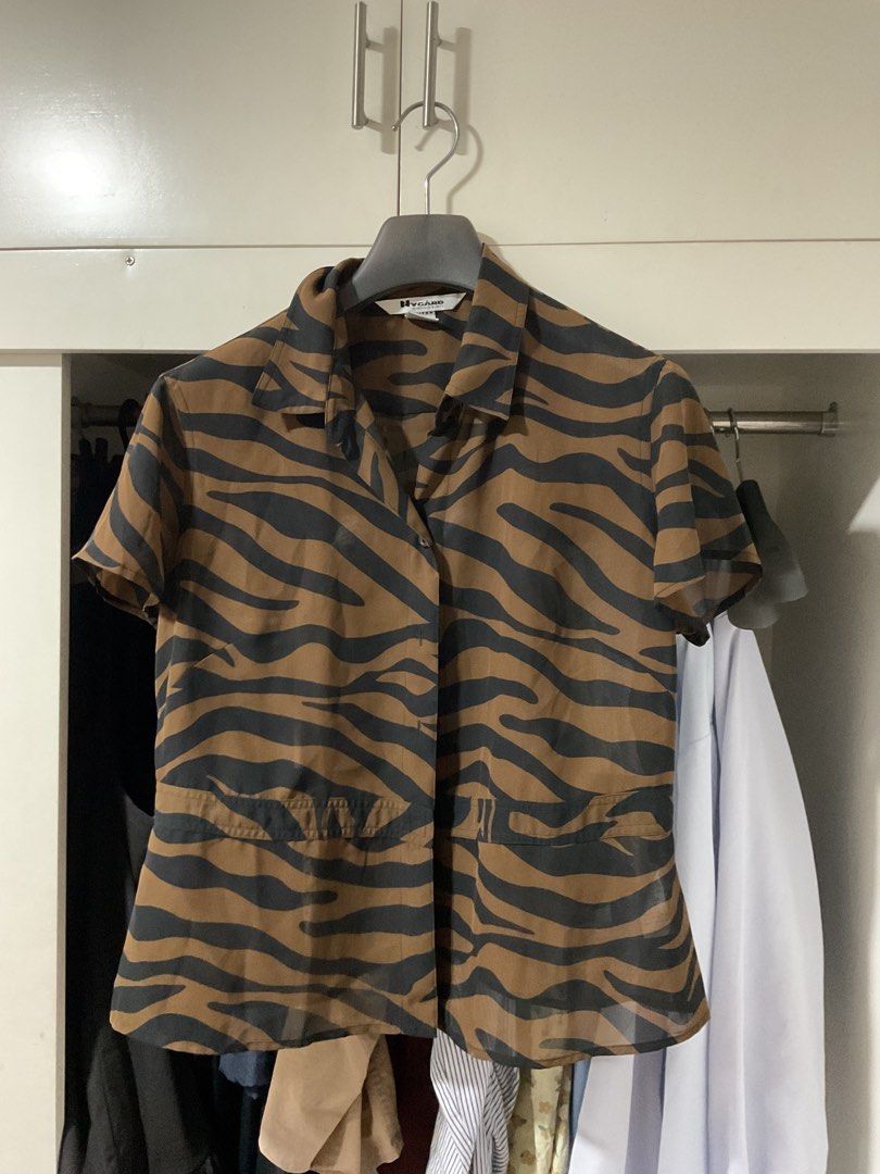 Brown Tiger Print Button-Up Blouse (Category: Blouses) located in Bulacan. Submitted by periwinkle_21 (Listing ID 1447867165, Image 1). Description: - Cool brown and black tiger print blouse - Short sleeves - Collared neckline - Two front pockets - Sheer material, ideal for layering - Perfect for summer wear since sheer.