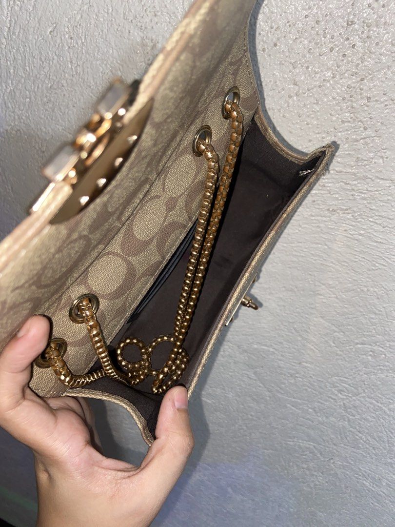 Coach Signature Canvas Chain Shoulder Bag (Category: Luxury Bags & Wallets) located in Lopez. Submitted by hariya00 (Listing ID 1447728798, Image 3). Description: - Coach mini shoulder bag in brown signature canvas - Gold-tone chain strap, eyelets, and front turn-lock style hardware - Flap closure with rounded rectangular shape - Dark fabric interior with open main compartment - Visible wear includes fading/discoloration on canvas, edge wear, and