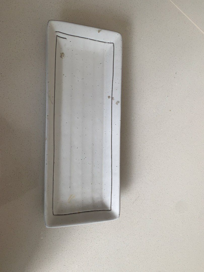 FREE Rectangular Ceramic Serving Dish (Category: Dinnerware & Cutlery) located in Singapore. Submitted by kshekar (Listing ID 1447720629, Image 1). Description: - White rectangular ceramic dish - Simple black border design - Ideal for serving snacks or small dishes - Textured brown edge on the bottom - Dimensions: Approx. [insert length] x [insert width] x [insert height].