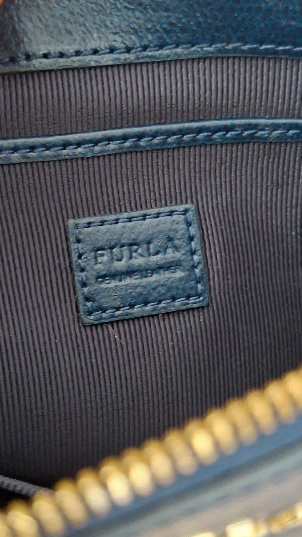 Furla Navy Leather Clutch Bag (Category: Luxury Bags & Wallets) located in Pasay City. Submitted by chaserstar (Listing ID 1447728830, Image 2). Description: Authentic Navy blue leather clutch from Furla. Zip closure with wrist strap. Some marks and scuffs on the exterior, shown in photos. Leather is slightly sticky due to storage. Interior is clean. Great for essentials and for repainting. Original is priced at around $150. Super steal!.