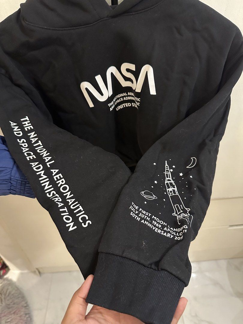 H&M Divided Black NASA Cropped Hoodie (Category: Coats, Jackets and Outerwear) located in Pasig City. Submitted by gwi0mi (Listing ID 1447873421, Image 2). Description: H&M Divided black cropped hoodie Size: Medium (M) Length: 18in Width: 21.5in Sleeve length: 30.5in • Features a NASA graphic on the front • Sleeve details include 'The National Aeronautics and Space Administration' • Graphic celebrates the Apollo 11 moon landing • Drawstring at th
