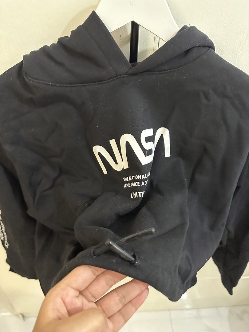 H&M Divided Black NASA Cropped Hoodie (Category: Coats, Jackets and Outerwear) located in Pasig City. Submitted by gwi0mi (Listing ID 1447873421, Image 3). Description: H&M Divided black cropped hoodie Size: Medium (M) Length: 18in Width: 21.5in Sleeve length: 30.5in • Features a NASA graphic on the front • Sleeve details include 'The National Aeronautics and Space Administration' • Graphic celebrates the Apollo 11 moon landing • Drawstring at th