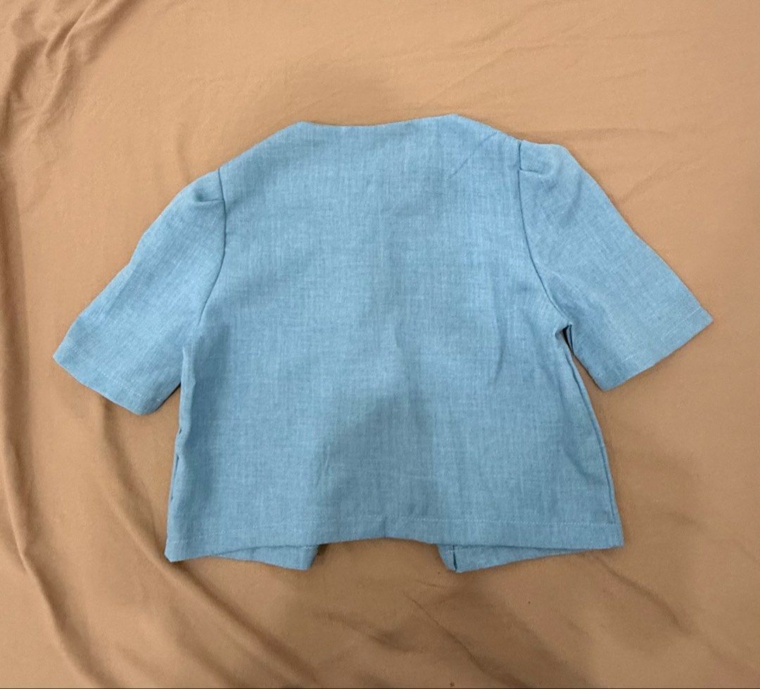 Light Blue Button-Up Cropped Blouse with Puff Sleeves (Category: Blouses) located in Quezon City. Submitted by _cmls (Listing ID 1447818004, Image 2). Description: - Light blue cropped blouse - Short puff sleeves - Round neckline - Five buttons down the front - Subtle fabric texture - Perfect for pairing with high-waisted bottoms - Ideal for casual or slightly dressed-up occasions.