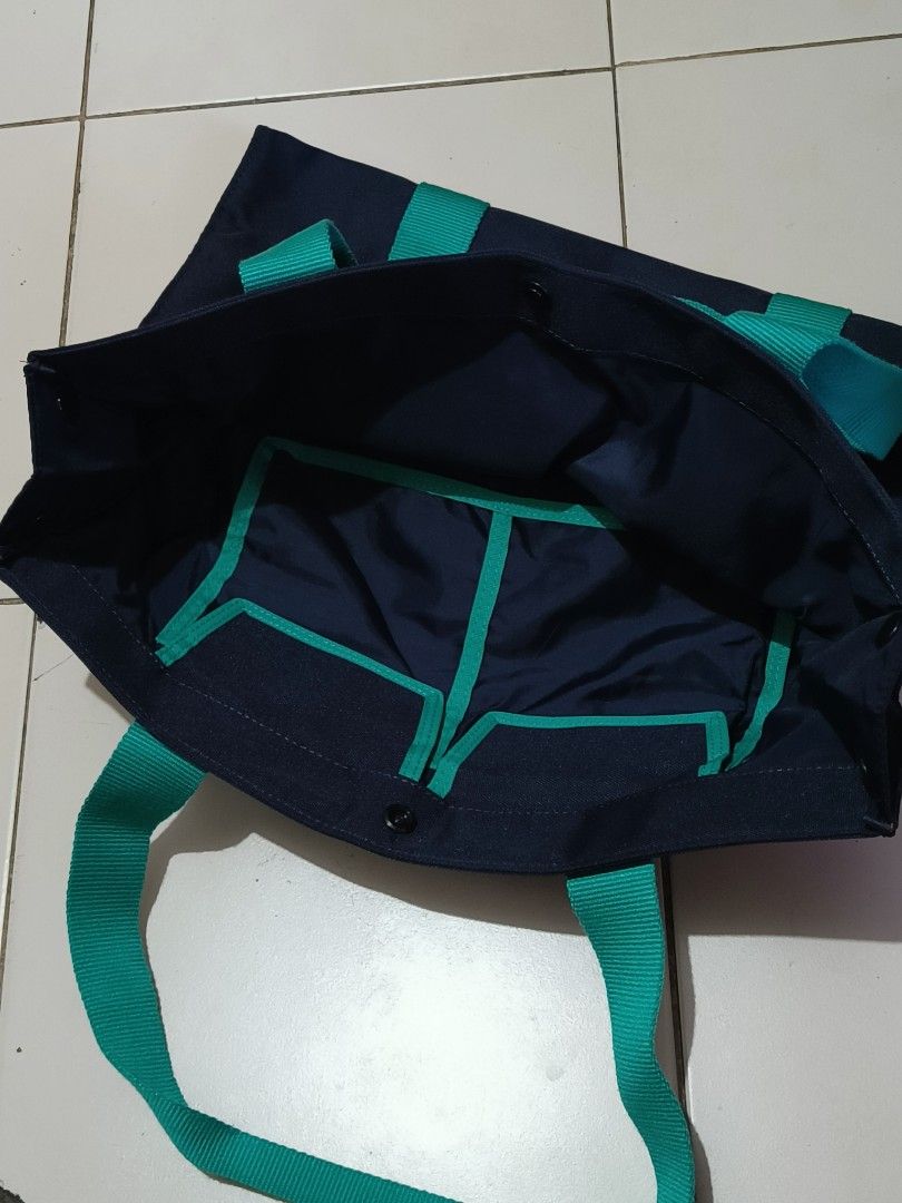 Mariners Navy Blue Tote Bag with Teal Straps (Category: Tote Bags) located in Manila. Submitted by bigtym.picker (Listing ID 1447705317, Image 3). Description: - Navy blue tote bag - Teal straps - Mariners logo on front - Multiple interior compartments for organization - Snap button closure - Ideal for everyday use or shopping.